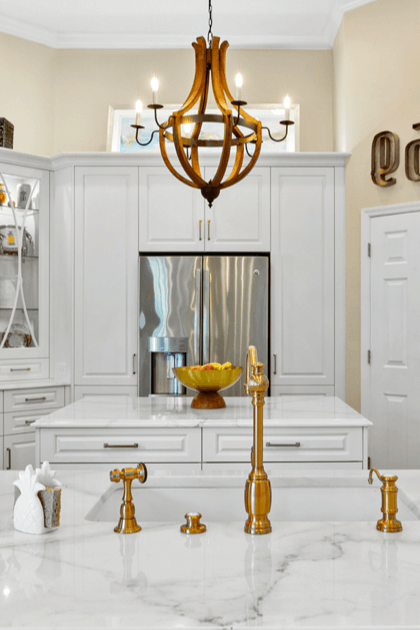 Luxury white kitchen with gold faucets and wooden chandelier