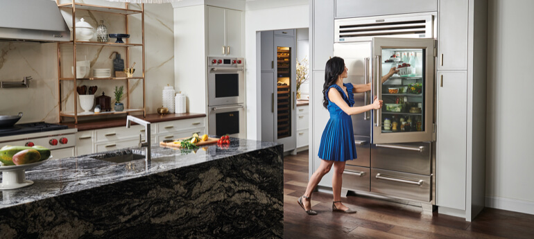 Woman in luxury kitchen putting food in refrigerator