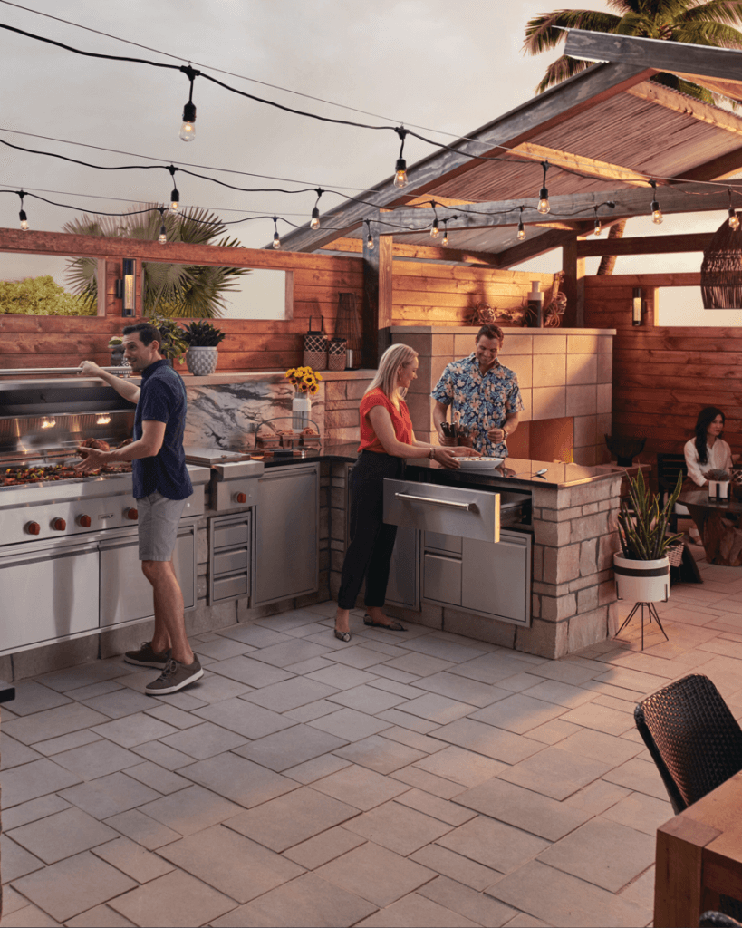 Small group of adults using luxury outdoor kitchen for dinner