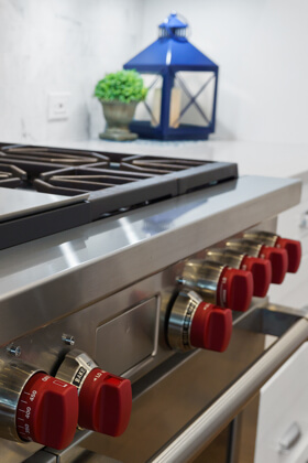 Closeup of stainless steel oven with red knobs
