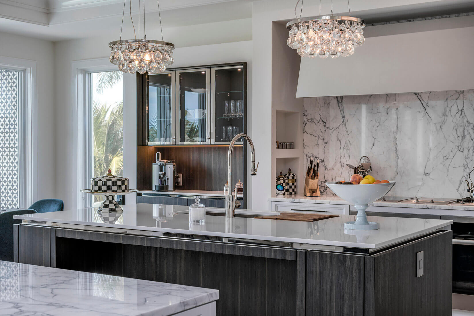 Upscale kitchen with elegant island, chandeliers and marble backsplash