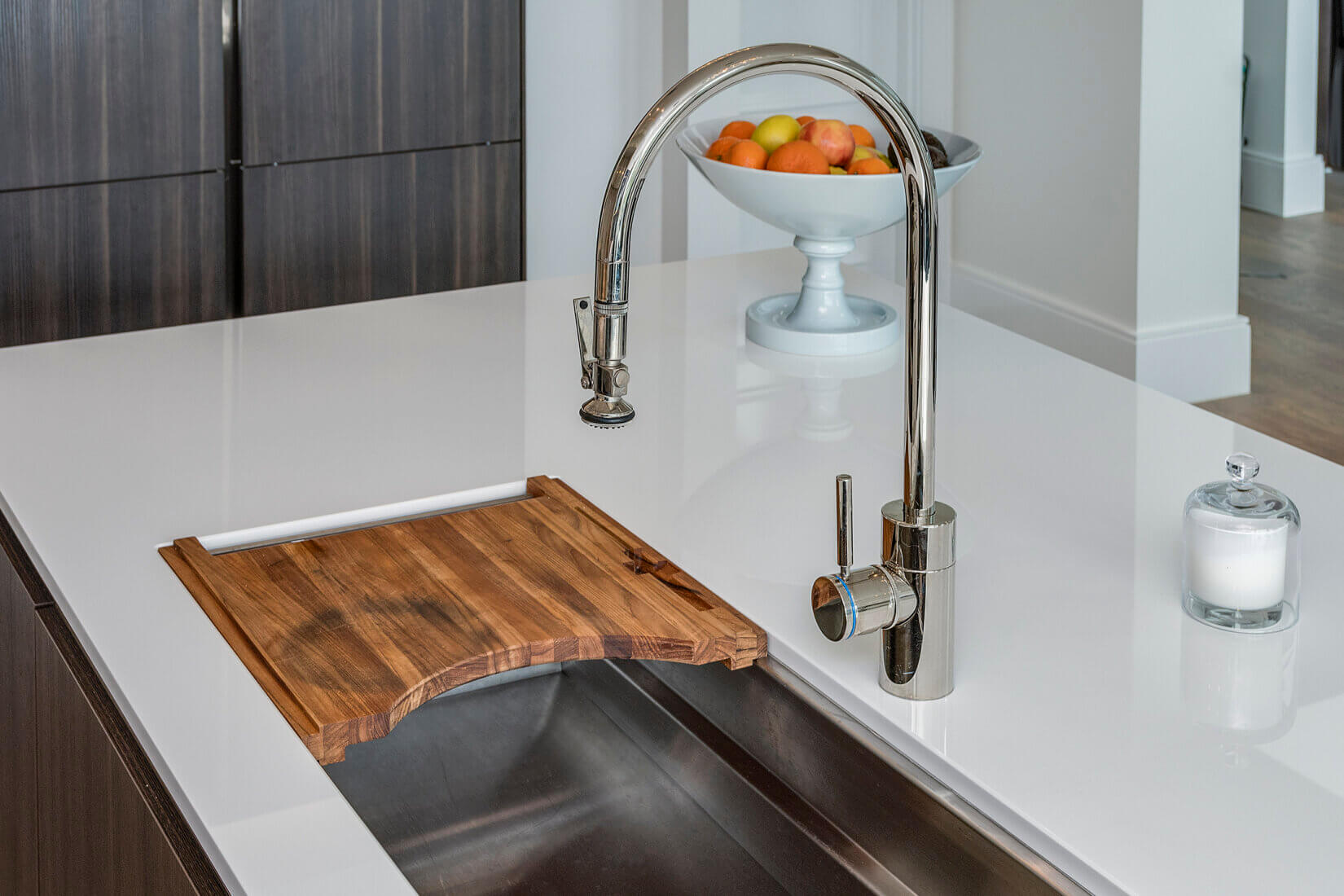 Closeup of pulldown spray faucet and built-in cutting board in kitchen
