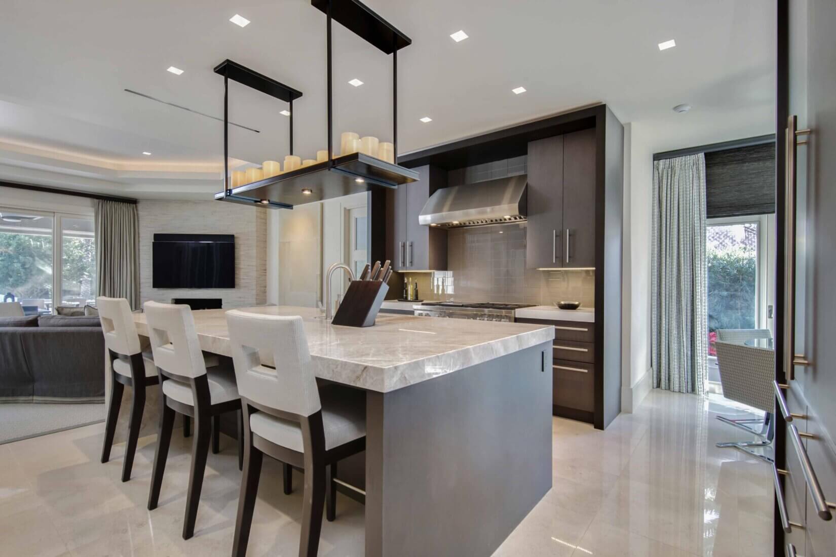 Luxury kitchen and dining space with dark-wood cabinetry and white marble counters