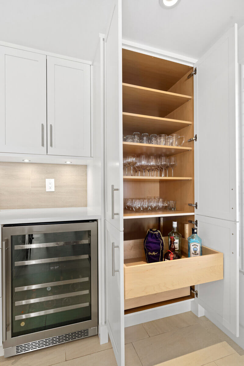 Large cabinet space with wine and beverage glasses stored inside next to wine cooler