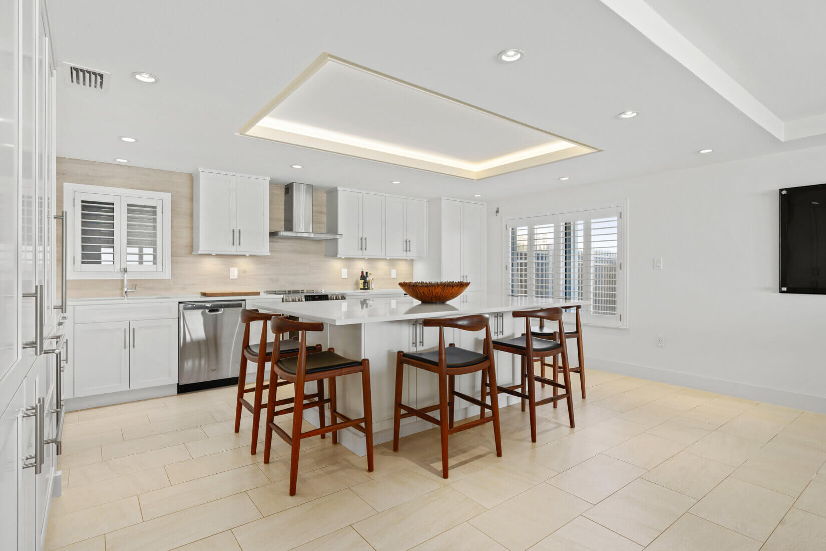 Sleek white kitchen with tall cabinetry and a spacious island with seating around it