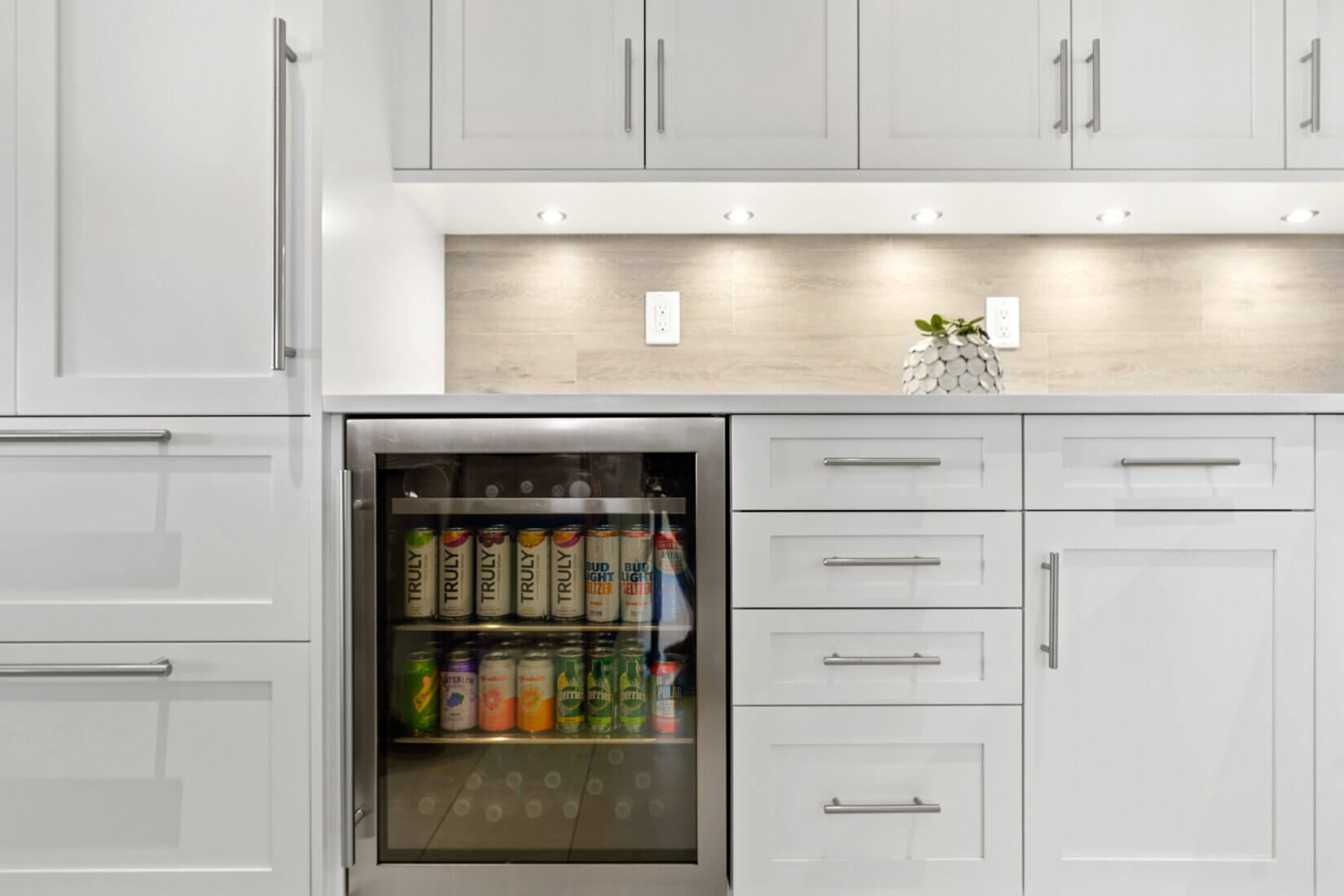 Mini refrigerator with drinks installed into cabinetry of luxury white kitchen