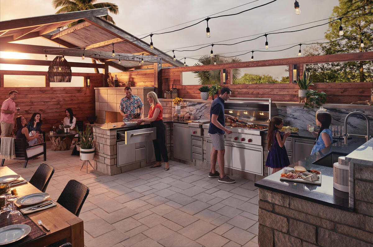 Group of people enjoying luxury outdoor kitchen with stone and wood finishes